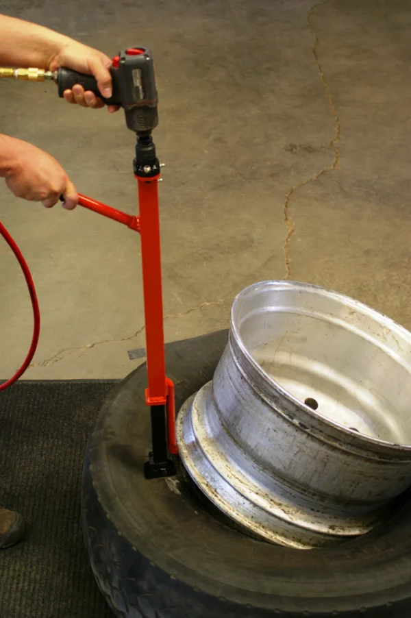 Technician using Pneu-Tek Impact Wheel Demounter to remove tire from agricultural wheel